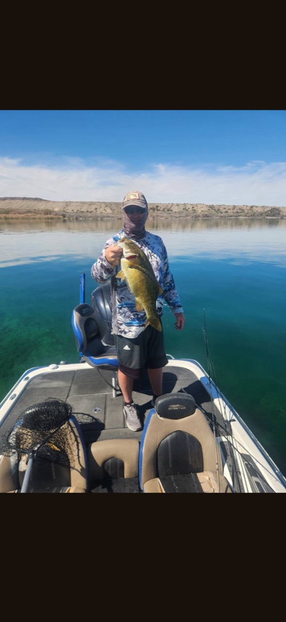 An angler showing a bass on a boat in clear lake water